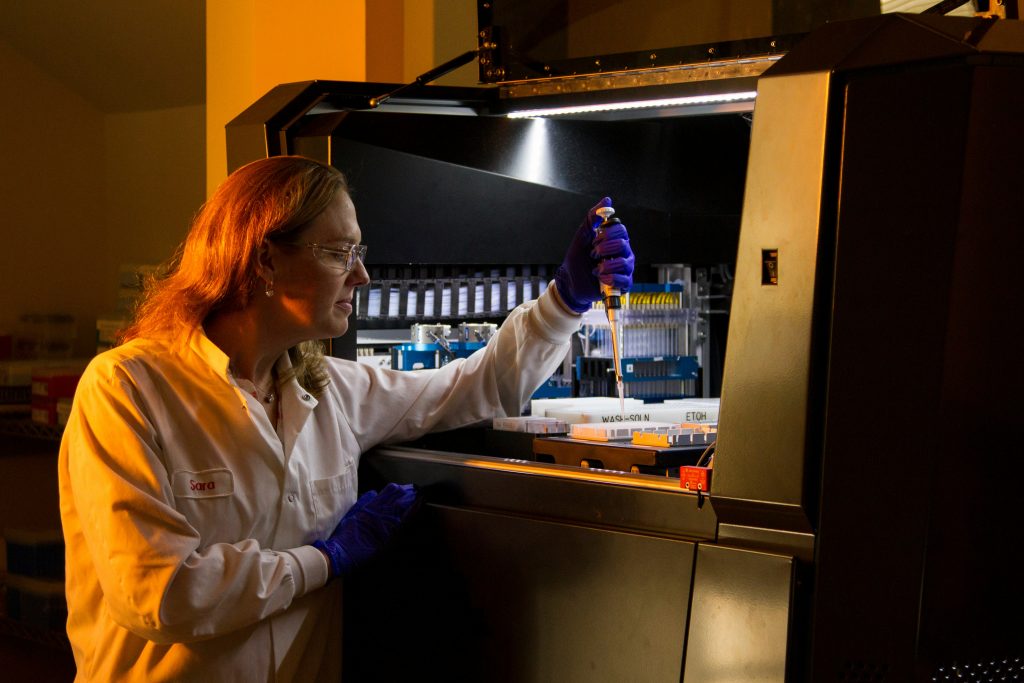 Laboratory researcher examining research peptide vials and scientific samples in a controlled laboratory environment.